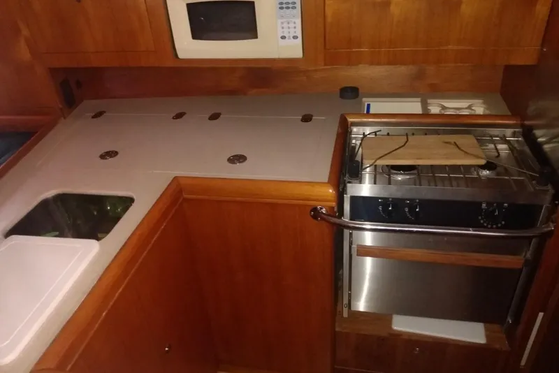Slide: The Image of Compact kitchen area in a 2003 Hunter 356 sailboat with stove, sink, and microwave. - 15