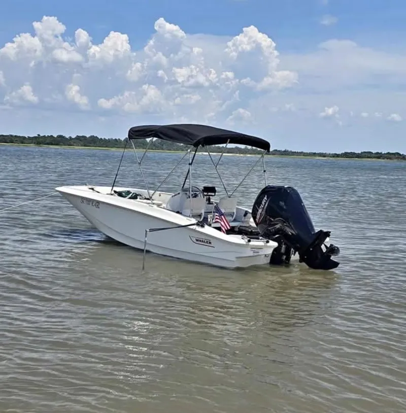 The Image of A 2021 Boston Whaler 160 Super Sport with a black Bimini top on calm water. - 7