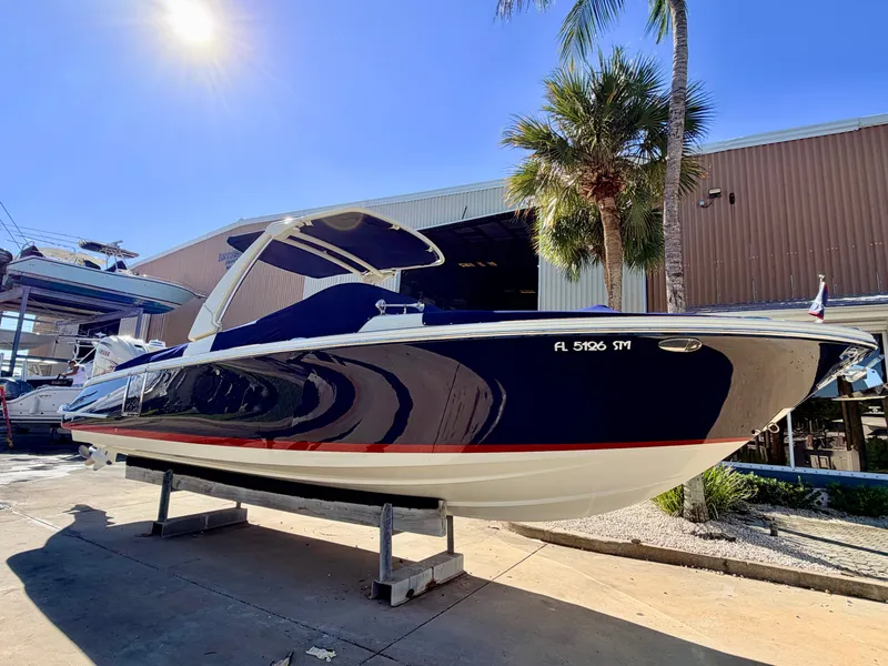 Slide: The Image of 2019 Chris-Craft Launch 28 GT OB in a boatyard, featuring a blue hull with a red stripe. - 15