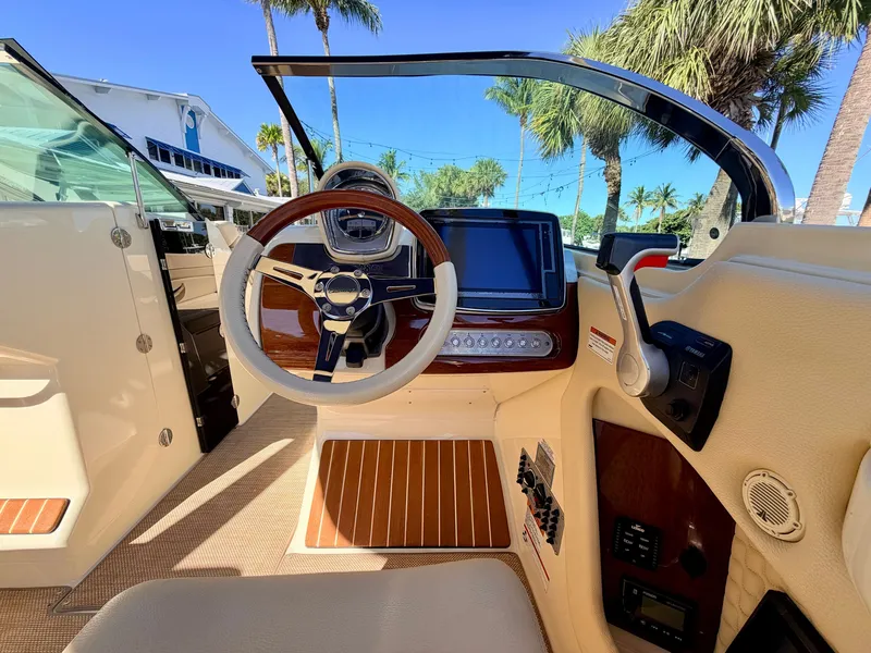 Slide: The Image of The cockpit of a 2019 Chris-Craft Launch 28 GT OB with a sleek steering wheel and modern instruments. - 48