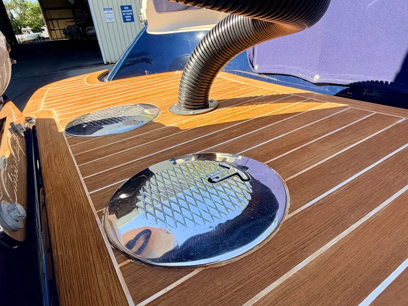 Slide: The Image of Close-up of the teak deck on a 2019 Chris-Craft Launch 28 GT OB with shiny metal accents. - 25