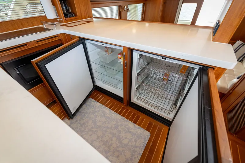 Slide: The Image of Luxurious 2019 Marlow Explorer 49E yacht kitchen with open fridge and freezer, elegant wood finish. - 47
