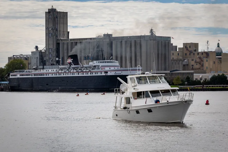 Slide: The Image of 2019 Marlow Explorer 49E yacht on water, industrial backdrop with large ship and buildings. - 11