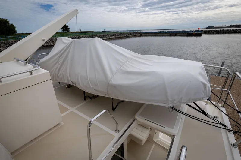 Slide: The Image of 2019 Marlow Explorer 49E yacht with covered equipment on deck, docked by a calm waterfront. - 77