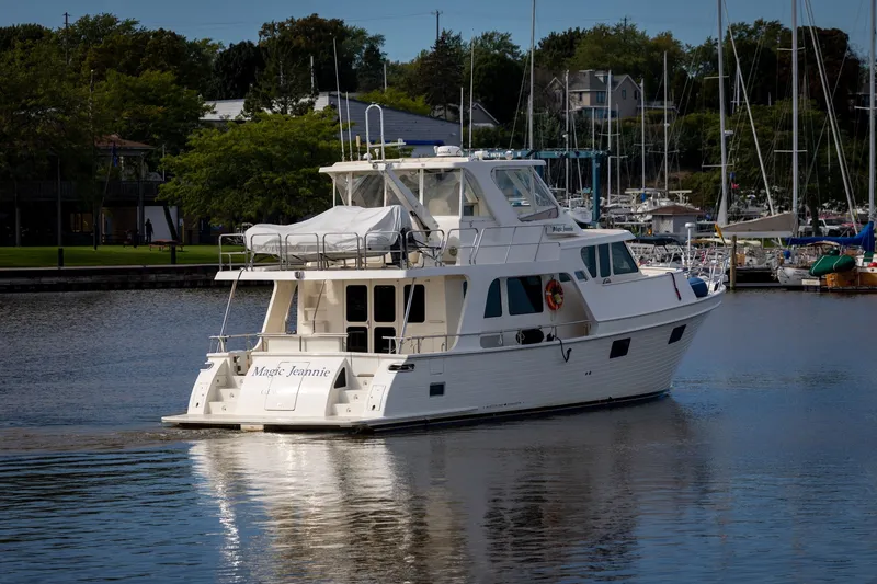 Slide: The Image of 2019 Marlow Explorer 49E yacht cruising in a marina, surrounded by sailboats and greenery. - 2