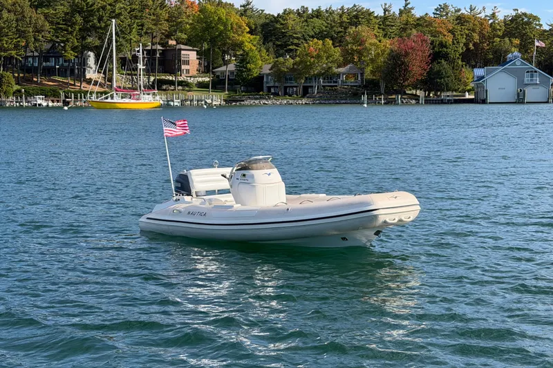 Slide: The Image of 2004 Nautica RIB 15 Widebody boat on a serene lake with scenic background. - 3
