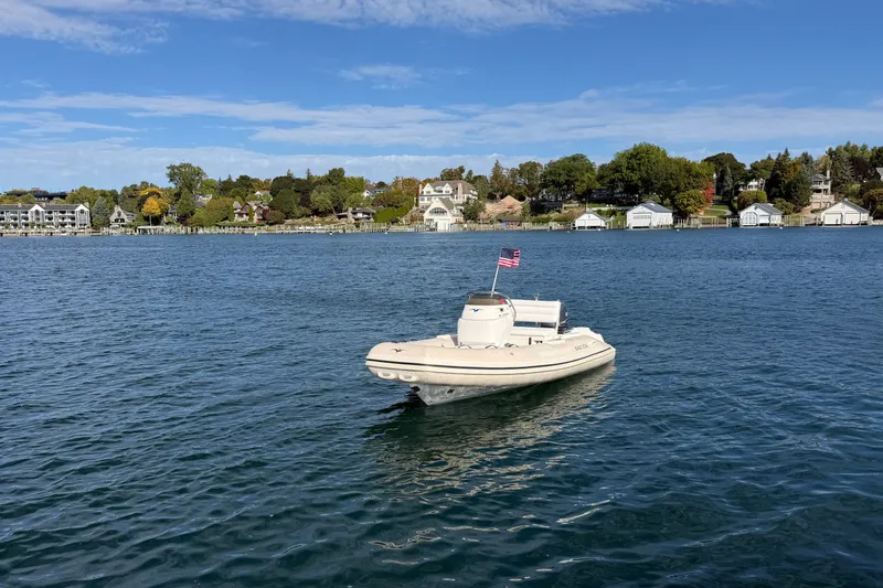 Slide: The Image of 2004 Nautica RIB 15 Widebody boat on a serene lake with houses in the background. - 13
