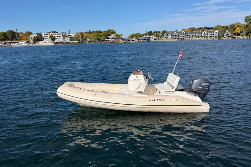 Slide: The Image of 2004 Nautica RIB 15 Widebody boat on calm water with shoreline in background. - 11