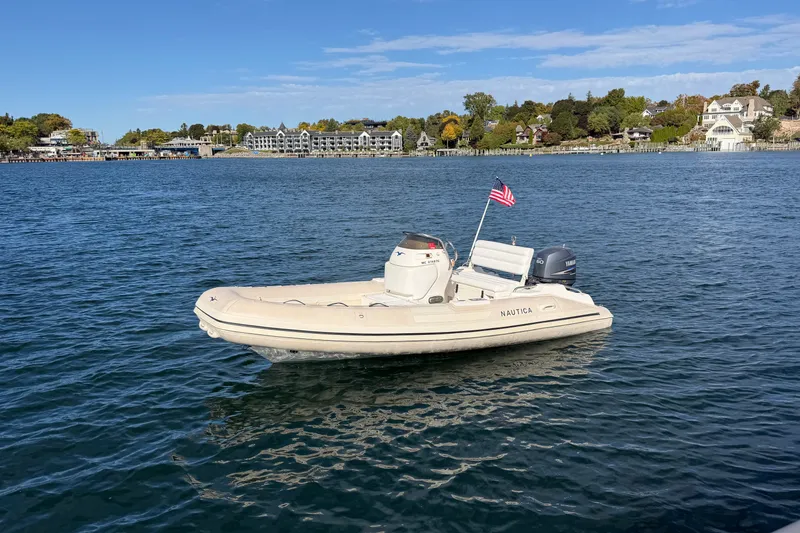 Slide: The Image of 2004 Nautica RIB 15 Widebody boat on calm water with American flag. - 12