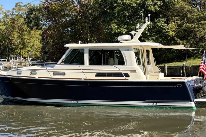 The Image of 2010 Sabre 40 Sedan yacht on calm water, surrounded by lush greenery. - 0
