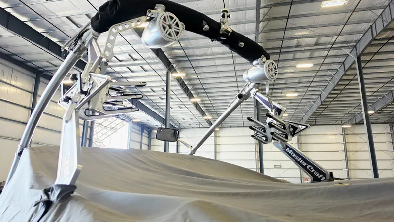 Slide: The Image of A 2010 MasterCraft X-55 in a warehouse, covered, with speakers on the wakeboard tower. - 13