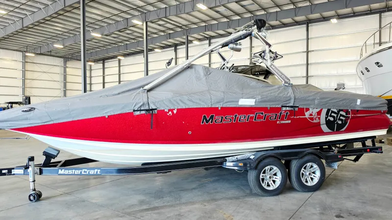 Slide: The Image of A red 2010 MasterCraft X-55 boat sits on a trailer in a warehouse. - 14