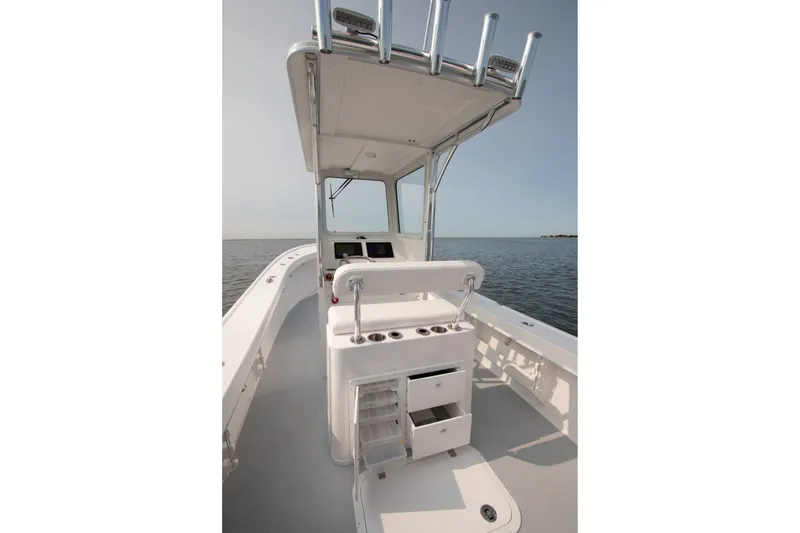 Slide: The Image of 2027 Steiger Craft 23 Chatham boat interior with helm and storage, on calm water. - 3