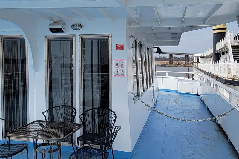 Slide: The Image of 1978 Blount Passenger ship deck with chairs and table, overlooking water and bridge. - 21