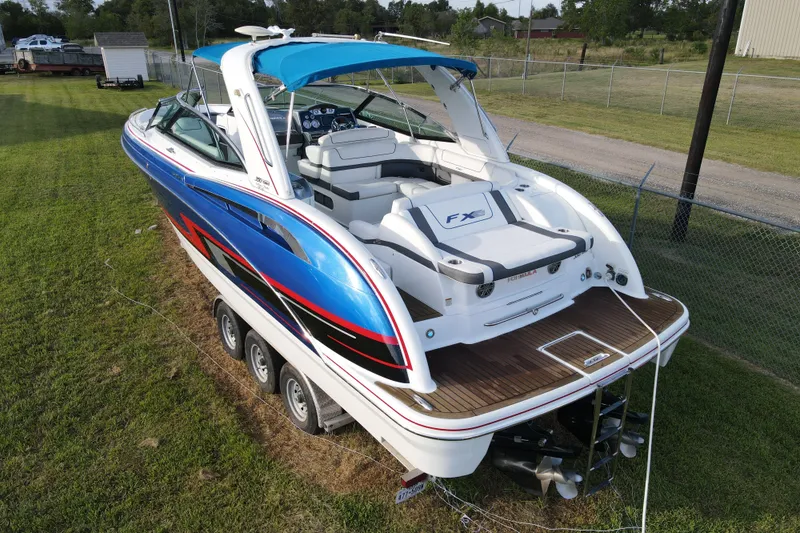 Slide: The Image of 2015 Formula 350 FX Crossover Bowrider boat with vibrant blue and white design on grass. - 17