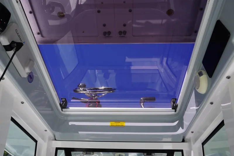 Slide: The Image of 2024 Sportsman Masters 267OE Bay Boat interior with blue-tinted sunroof and steering wheel. - 47