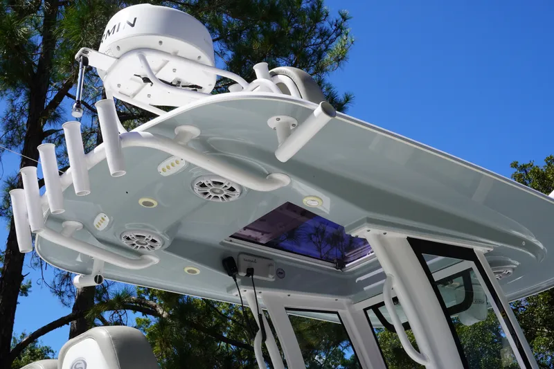 Slide: The Image of 2024 Sportsman Masters 267OE Bay Boat T-top with rod holders and electronics against blue sky. - 27