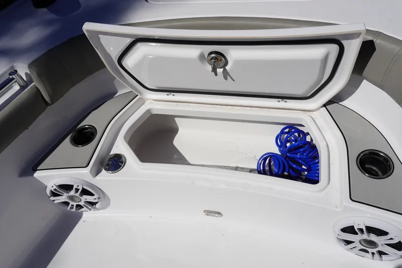 Slide: The Image of 2024 Sportsman Masters 267OE Bay Boat storage compartment with speakers and coiled hose. - 38