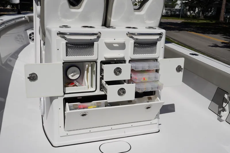 Slide: The Image of 2024 Sportsman Masters 267OE Bay Boat storage compartments with tackle boxes and fishing gear. - 24
