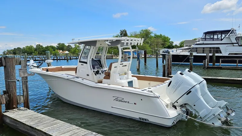 The Image of A 2022 Pioneer 270 Pelagic boat docked. It features a white hull and twin outboard engines. - 0