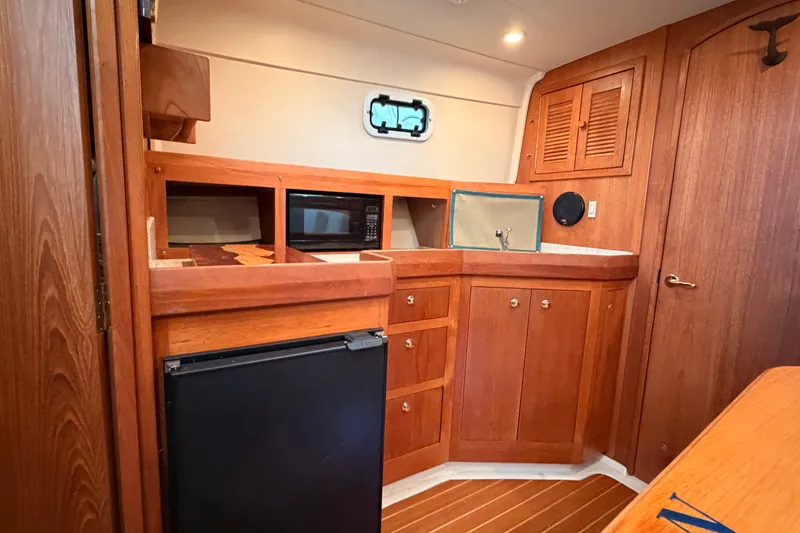 Slide: The Image of Interior of 2001 Mainship Pilot 34 boat with wooden cabinetry and compact kitchen area. - 24