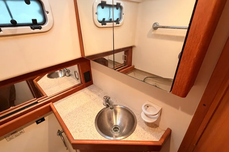 Slide: The Image of 2001 Mainship Pilot 34 bathroom with stainless steel sink, mirror, and porthole window. - 28