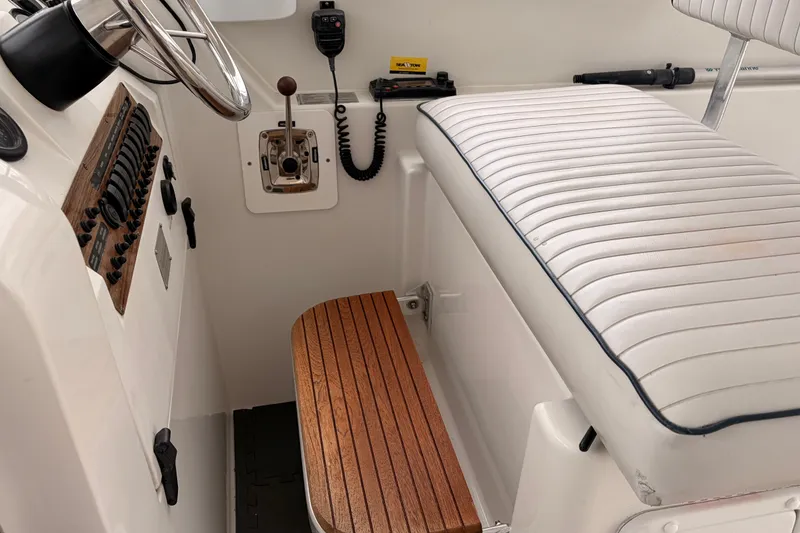 Slide: The Image of 2001 Mainship Pilot 34 helm with white seating and wooden footrest. - 15