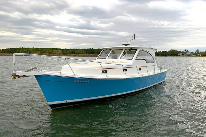 The Image of 2001 Mainship Pilot 34 boat on water, blue hull, overcast sky. - 1