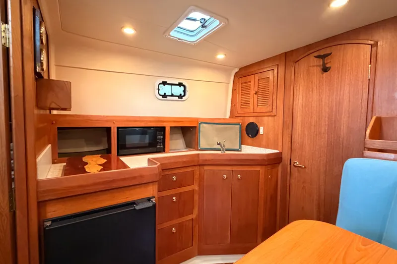 Slide: The Image of 2001 Mainship Pilot 34 interior with wooden cabinetry, microwave, and compact kitchen area. - 23