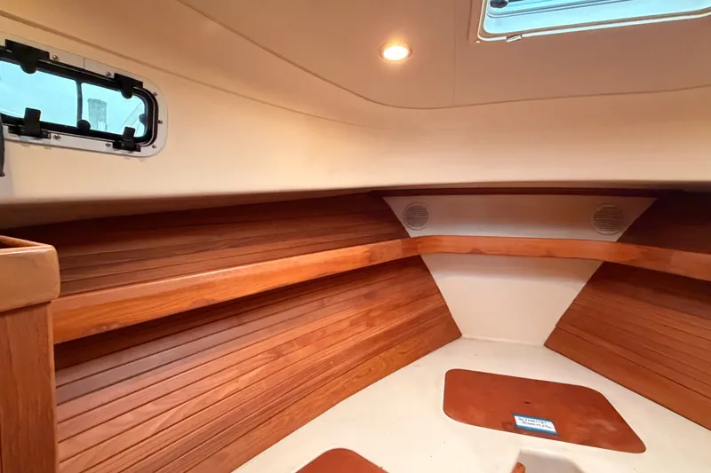 Slide: The Image of Interior of 2001 Mainship Pilot 34 boat, featuring wood paneling and a porthole window. - 37