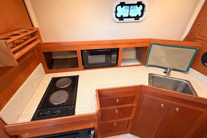 Slide: The Image of 2001 Mainship Pilot 34 galley with stove, microwave, and sink. - 25