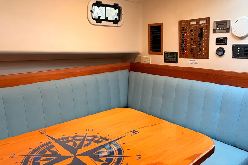 Slide: The Image of Cozy interior of 2001 Mainship Pilot 34 with compass-themed table and control panel. - 35