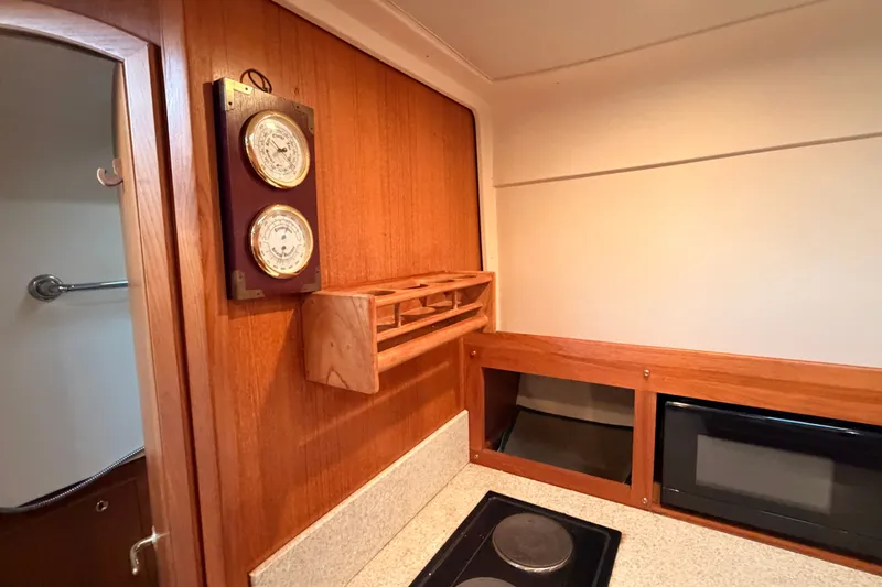 Slide: The Image of 2001 Mainship Pilot 34 interior with wooden paneling, barometer, and compact kitchen area. - 26