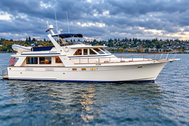 Slide: The Image of 1991 Tollycraft 61 Pilothouse Motor Yacht on scenic water with cloudy sky backdrop. - 2