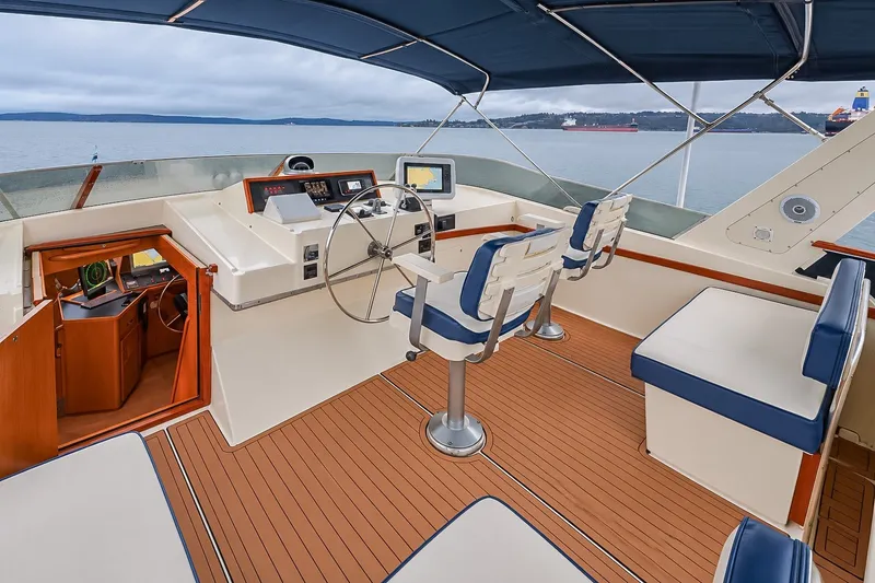 Slide: The Image of 1991 Tollycraft 61 Pilothouse Motor Yacht helm with seating, overlooking calm waters. - 50