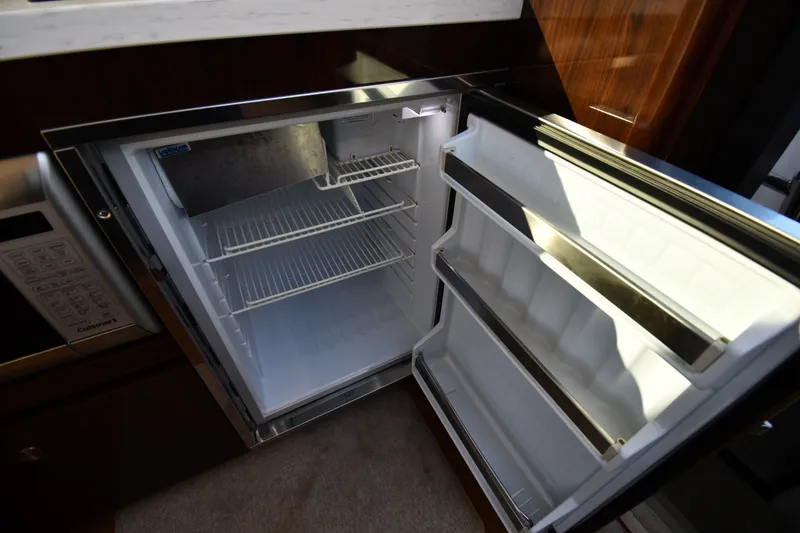 Slide: The Image of Open refrigerator inside 2017 Sea Ray Sundancer 400 yacht, showcasing interior storage space. - 46