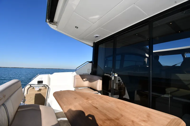 Slide: The Image of 2017 Sea Ray Sundancer 400 yacht deck with seating and table, overlooking calm waters. - 9