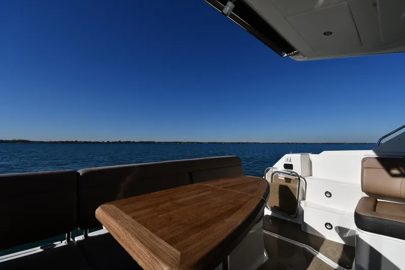 Slide: The Image of 2017 Sea Ray Sundancer 400 yacht interior with ocean view and wooden table. - 10