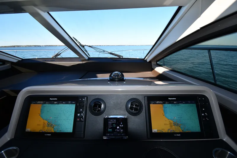 Slide: The Image of 2017 Sea Ray Sundancer 400 helm with navigation screens, overlooking calm waters. - 38