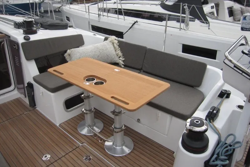 Slide: The Image of 2027 Jeanneau Sun Odyssey 455 cockpit with wooden table and cushioned seating. - 33