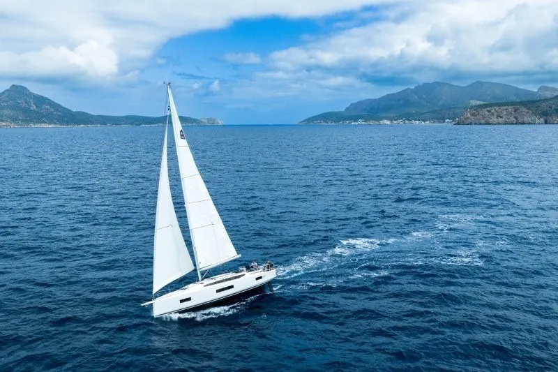 Slide: The Image of Sailing yacht Jeanneau Sun Odyssey 455, 2027 model, cruising on open sea with scenic mountain backdrop. - 51