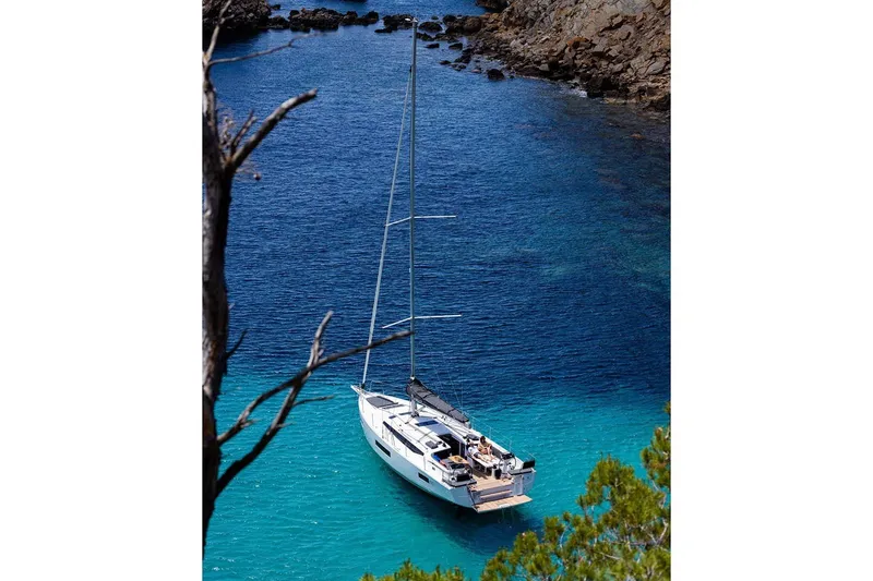 Slide: The Image of Manufacturer Provided Image: 2026 Jeanneau Sun Odyssey 455 yacht anchored in a serene, turquoise bay. - 46