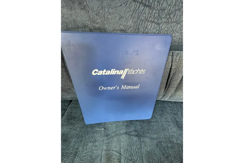 Slide: The Image of Catalina 310 2004 owner's manual cover on textured surface. - 24