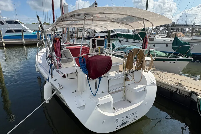 Slide: The Image of 2004 Catalina 310 sailboat docked at marina, featuring spacious deck and covered cockpit. - 2