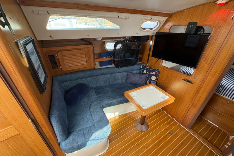 Slide: The Image of Interior of a 2004 Catalina 310 sailboat with cozy seating and a mounted TV. - 23