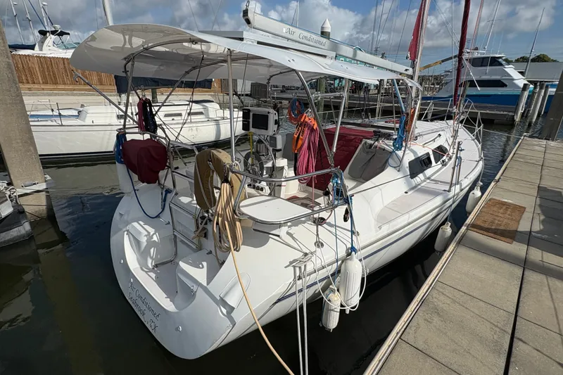 Slide: The Image of 2004 Catalina 310 sailboat docked at marina, featuring spacious cockpit and covered deck. - 4