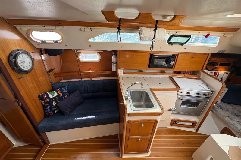 Slide: The Image of Interior of a 2004 Catalina 310 sailboat featuring a compact kitchen and cozy seating area. - 25