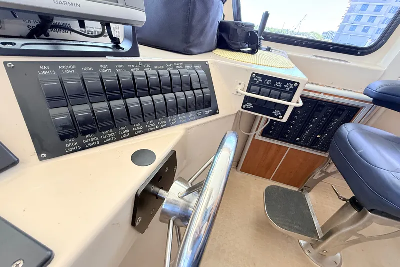 Slide: The Image of Control panel of a 2013 Silver Ships Inc Barrows 60 boat with various switches and steering wheel. - 23