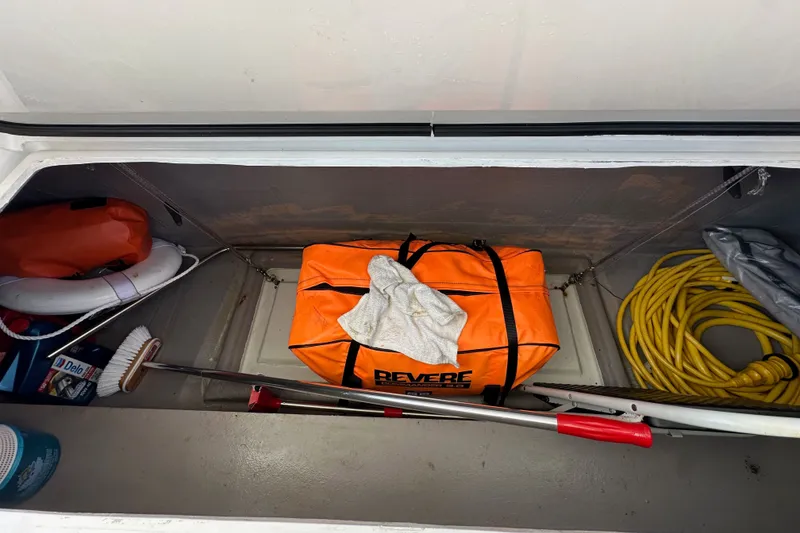 Slide: The Image of Storage compartment in a 2023 Bali 4.4 boat with safety gear and cleaning supplies. - 109