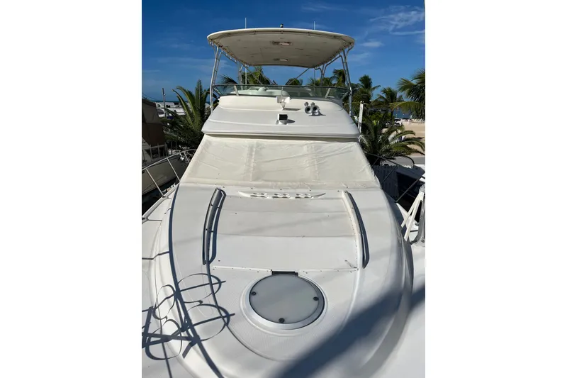 Slide: The Image of 1999 Maxum 4600 SCB yacht with sleek white deck and flybridge, surrounded by palm trees. - 31